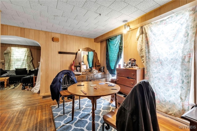 sitting room with arched walkways, wood walls, and hardwood / wood-style flooring