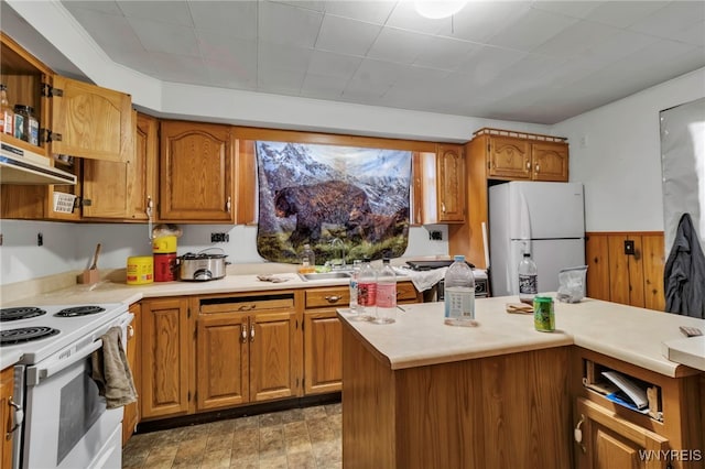 kitchen with brown cabinets, white appliances, under cabinet range hood, and light countertops