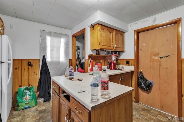 kitchen featuring freestanding refrigerator, a wainscoted wall, and wood walls