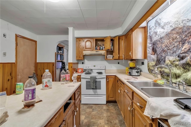 kitchen with white range with electric stovetop, wainscoting, light countertops, under cabinet range hood, and a sink