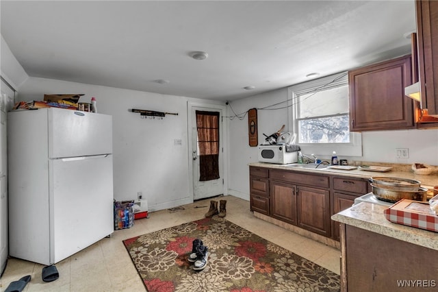 kitchen with light countertops, white appliances, a sink, and baseboards