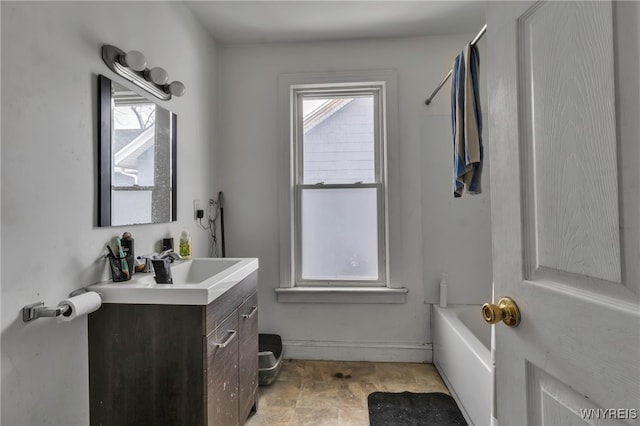 bathroom with a washtub, vanity, and baseboards