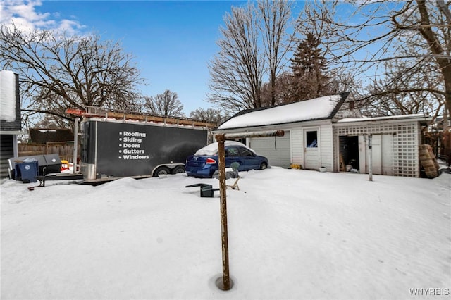 snow covered parking with an attached garage and fence