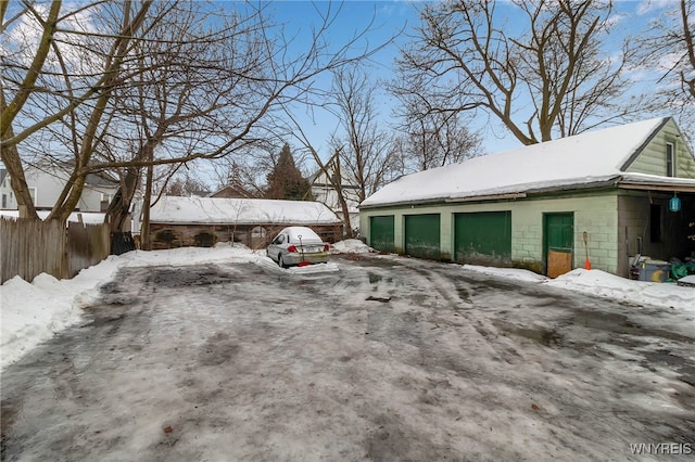 view of snow covered exterior featuring concrete block siding and fence