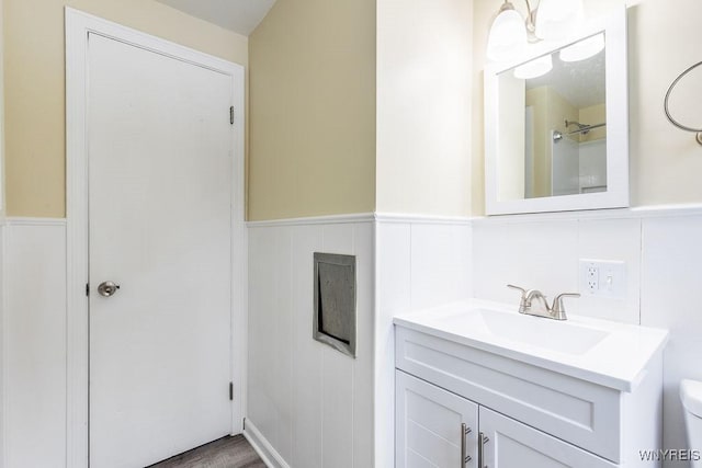 bathroom with toilet, a wainscoted wall, and vanity