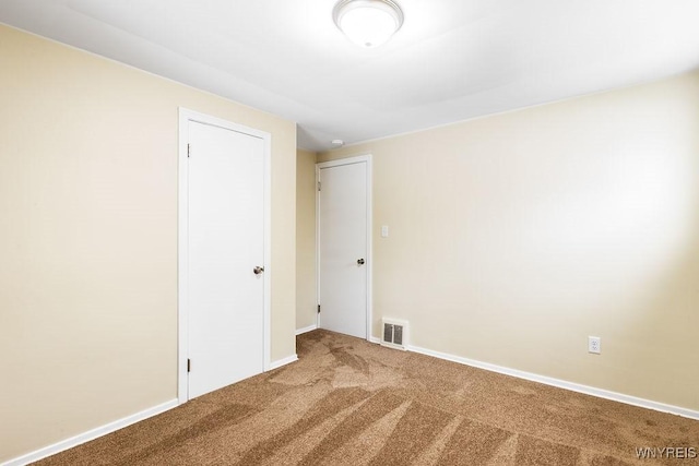 carpeted spare room with visible vents and baseboards