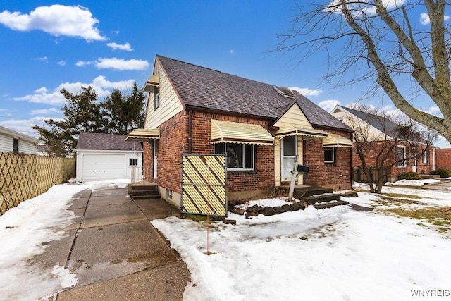 bungalow-style home with brick siding, a detached garage, roof with shingles, fence, and an outdoor structure