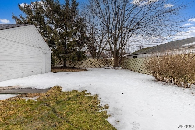 yard layered in snow featuring a garage and fence