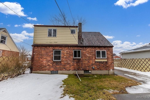 back of property featuring a shingled roof, a chimney, fence, and brick siding