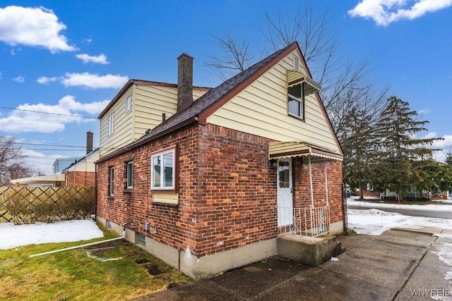 view of side of home featuring a chimney and brick siding