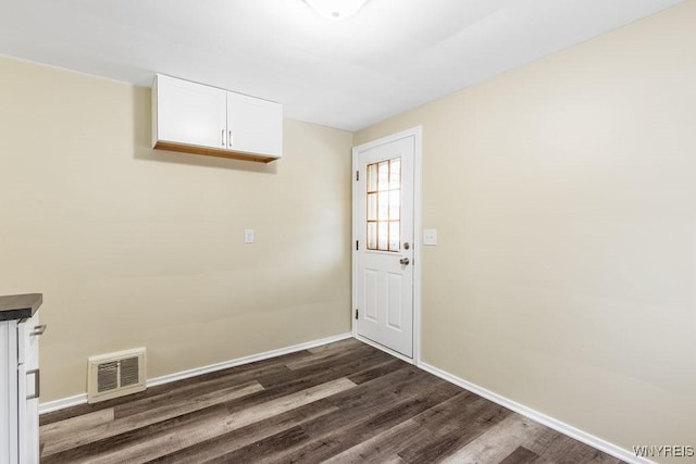 doorway with dark wood-style flooring, visible vents, and baseboards