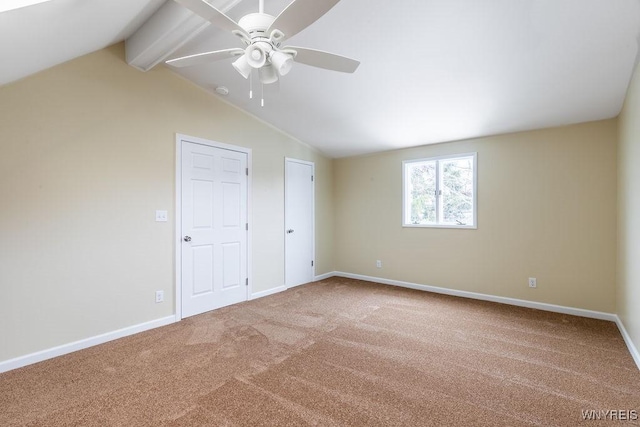 empty room featuring lofted ceiling with beams, carpet flooring, a ceiling fan, and baseboards