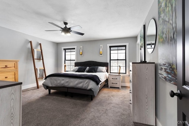 carpeted bedroom featuring a ceiling fan, multiple windows, and baseboards