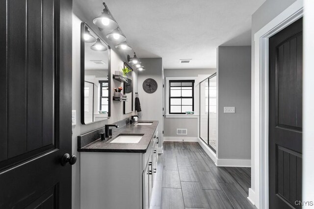 full bath with double vanity, a stall shower, a sink, and wood tiled floor