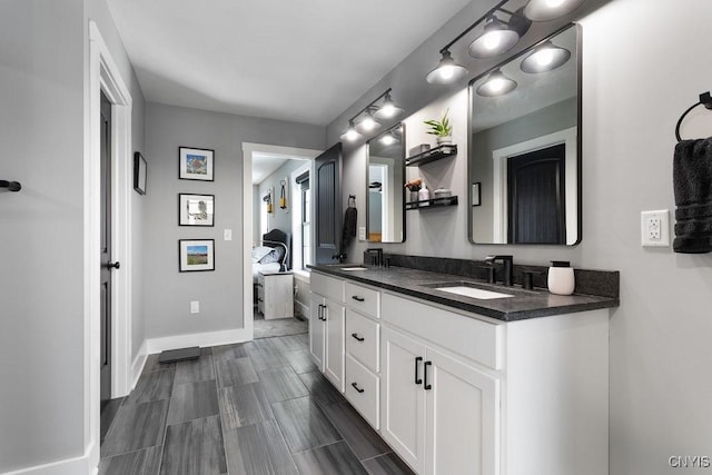 ensuite bathroom featuring double vanity, a sink, baseboards, and ensuite bathroom