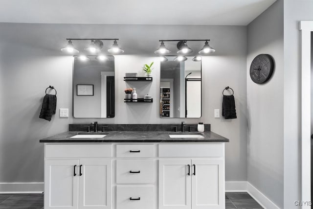 bathroom with double vanity, baseboards, and a sink