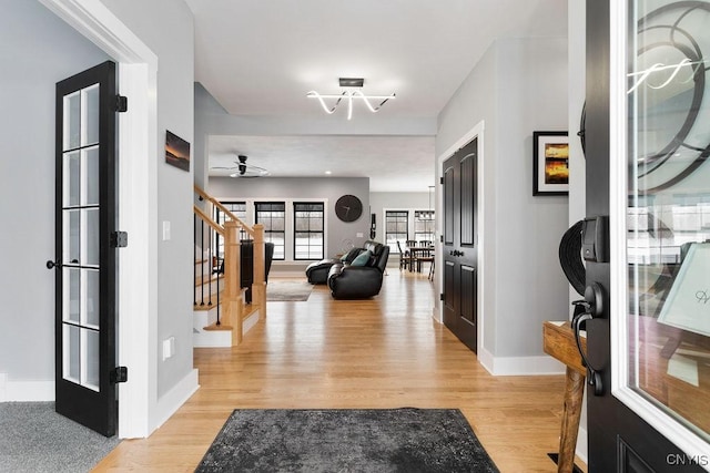 foyer with light wood-style floors, baseboards, and stairway