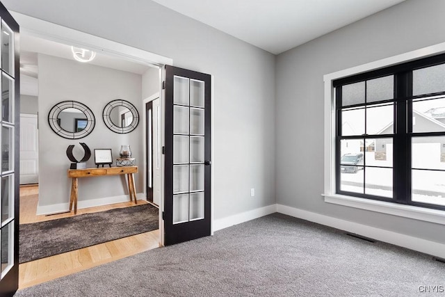 interior space with carpet floors, french doors, visible vents, and baseboards