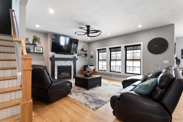 living area with recessed lighting, a fireplace, stairway, and wood finished floors