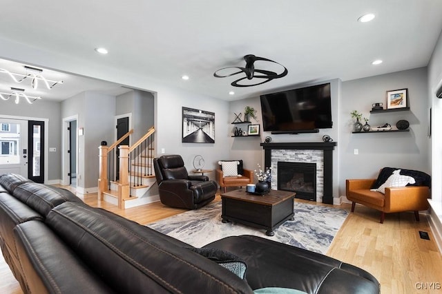 living area with baseboards, wood finished floors, stairs, a fireplace, and recessed lighting