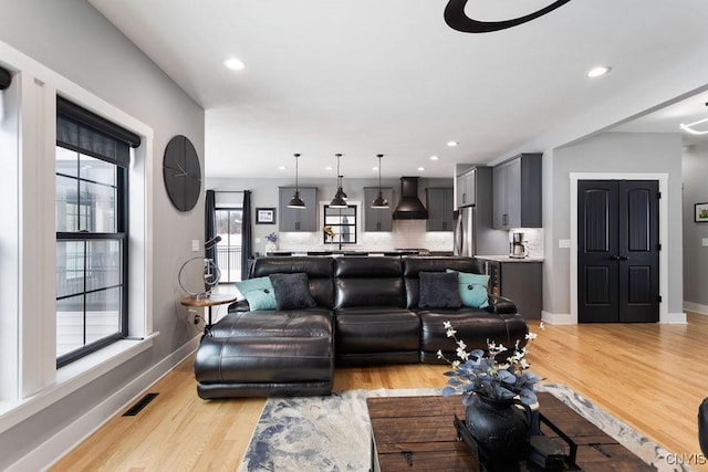 living room with light wood-style floors, recessed lighting, visible vents, and baseboards