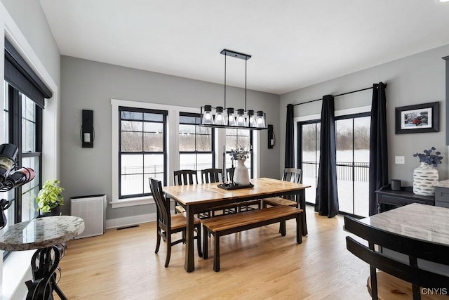 dining room featuring a healthy amount of sunlight, light wood finished floors, and visible vents