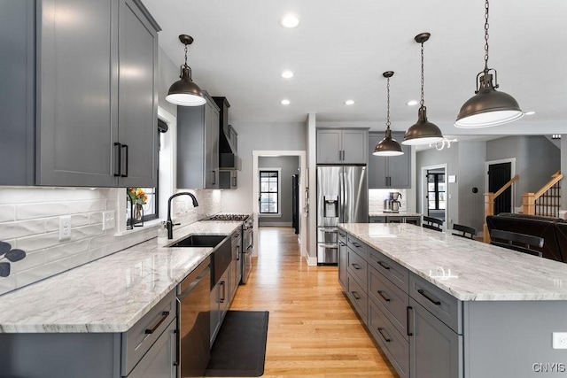 kitchen with stainless steel appliances, a spacious island, light stone counters, and gray cabinetry