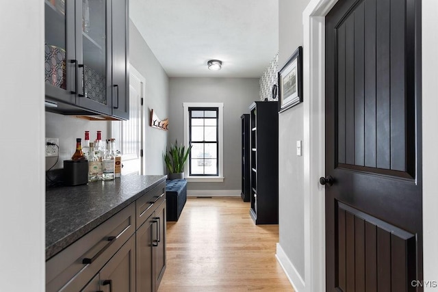 interior space with light wood-type flooring, baseboards, and a dry bar