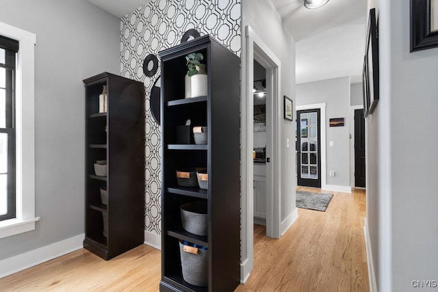 hall with light wood-style flooring and baseboards