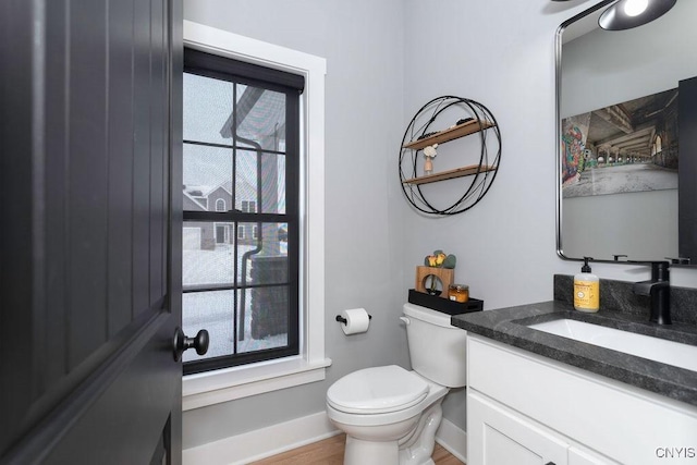 bathroom featuring toilet, baseboards, wood finished floors, and vanity