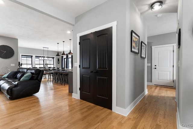 corridor with baseboards and light wood finished floors