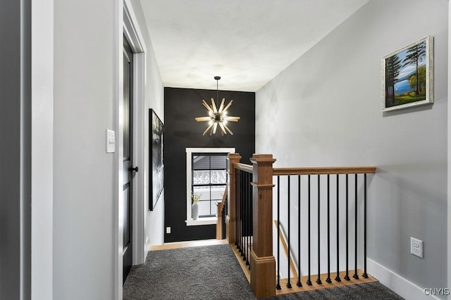 hallway featuring baseboards, an upstairs landing, and an inviting chandelier