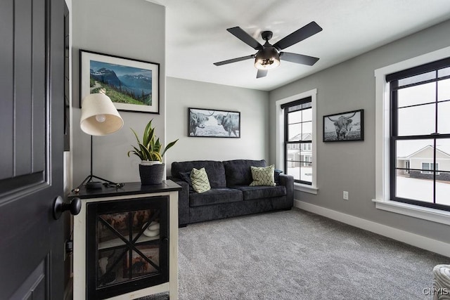 living area featuring carpet floors, a ceiling fan, and baseboards