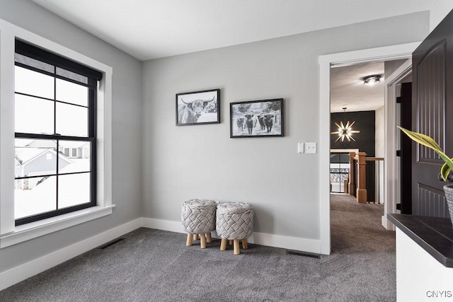 living area featuring visible vents, dark colored carpet, an upstairs landing, and baseboards