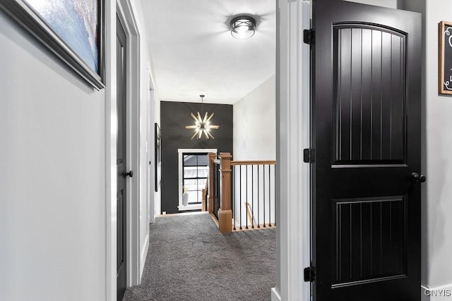 hall with a notable chandelier, carpet flooring, and an upstairs landing