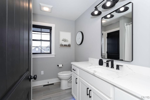 bathroom with baseboards, visible vents, vanity, and toilet