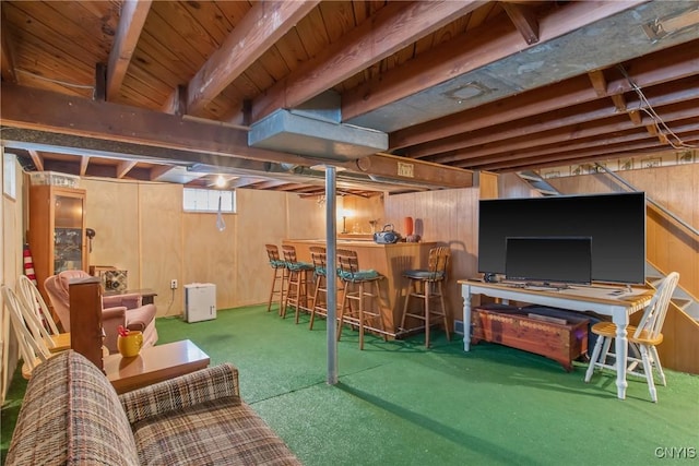 basement with a bar, wood walls, and carpet