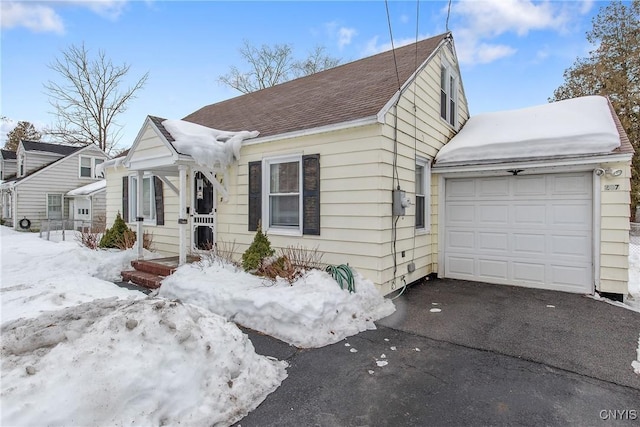 bungalow-style house featuring aphalt driveway, a shingled roof, and an attached garage