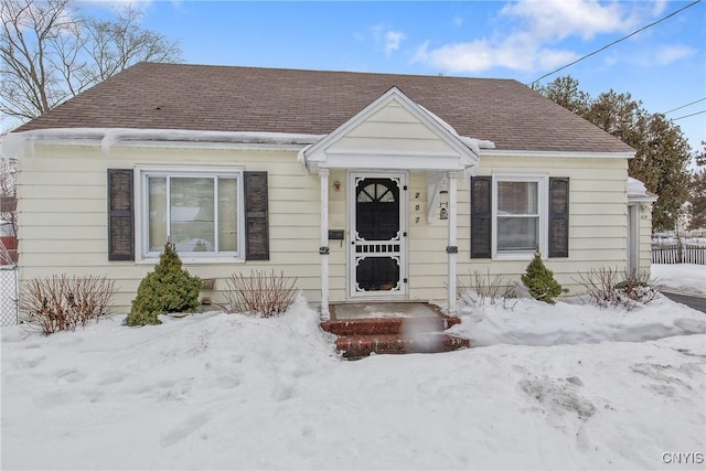 bungalow-style home featuring a shingled roof and fence