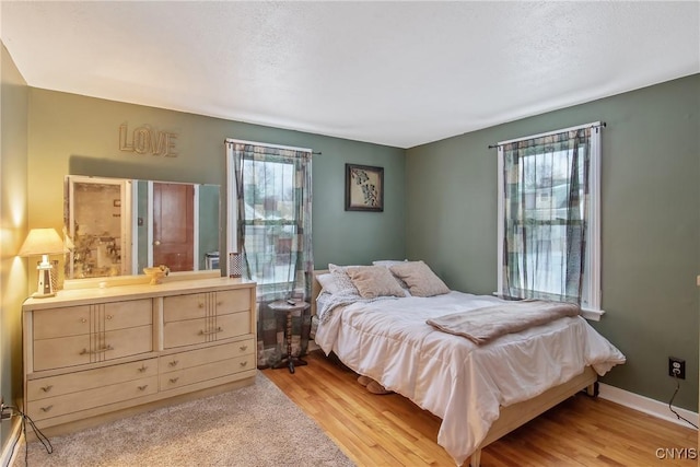 bedroom featuring light wood-style floors and baseboards