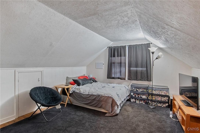 bedroom featuring lofted ceiling, carpet floors, and a textured ceiling