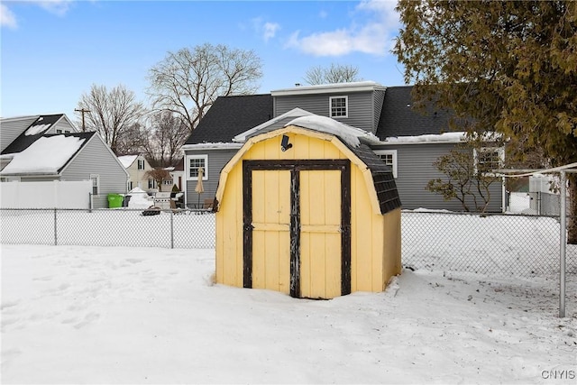 snow covered structure with a storage unit, an outdoor structure, and fence