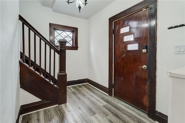 foyer entrance featuring baseboards, stairway, and wood finished floors