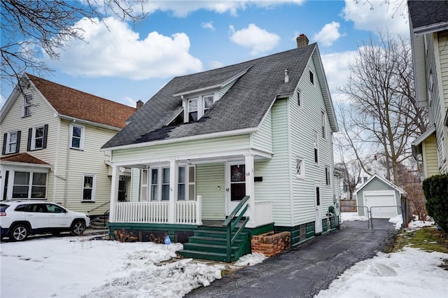 view of front facade featuring a garage, driveway, a chimney, an outdoor structure, and a porch