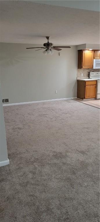 unfurnished living room with light carpet, ceiling fan, and baseboards