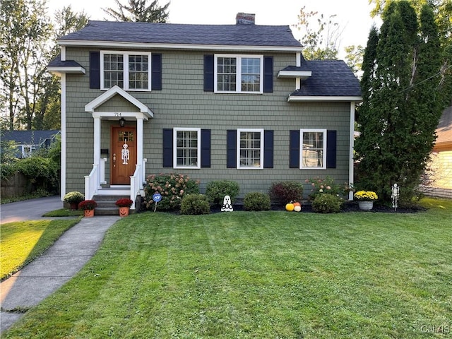 view of front of home featuring a shingled roof, a chimney, and a front lawn