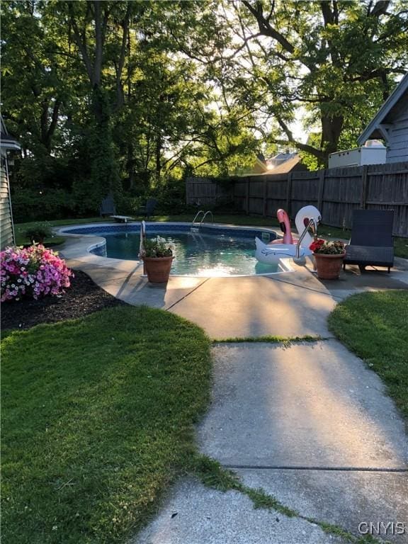 view of swimming pool featuring a patio, a yard, fence, and a fenced in pool