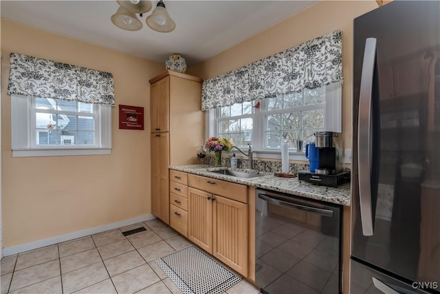 kitchen featuring light tile patterned flooring, a sink, visible vents, black dishwasher, and freestanding refrigerator