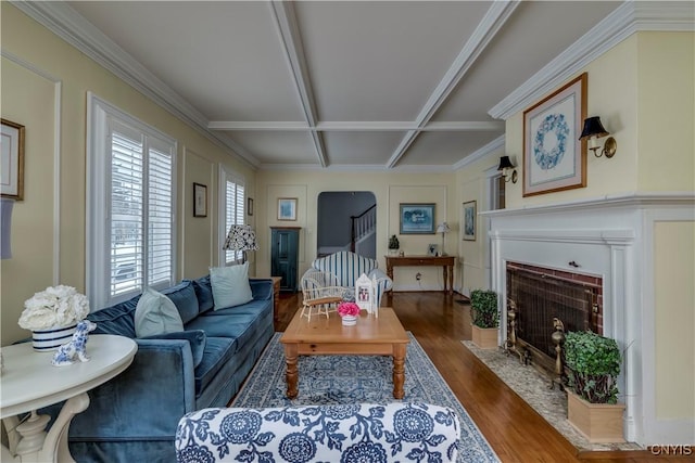 living area featuring a fireplace with flush hearth, stairway, arched walkways, and wood finished floors