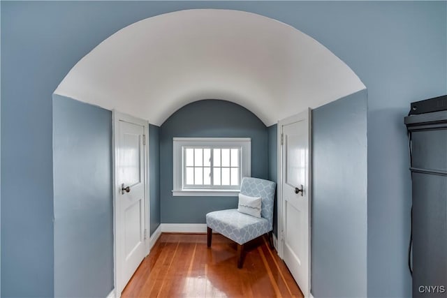 living area with vaulted ceiling, hardwood / wood-style floors, and baseboards